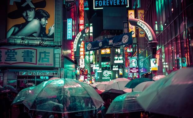 Straße in Tokyo bei Nacht, bunte Lichter, transparente Regenschirme