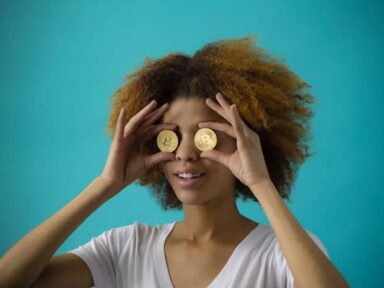 Frau hält sich zwei Bitcoinmünzen vor die Augen