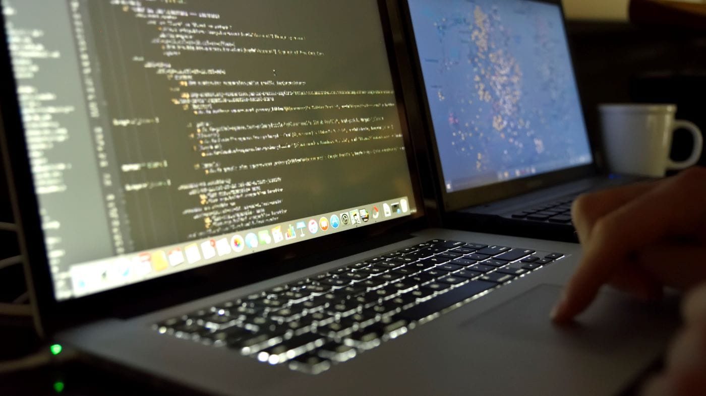 Zwei Laptops nebeneinander mit Code auf dem Bildschirm