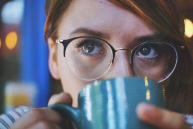Frau mit Brille trinkt aus einer blauen Tasse