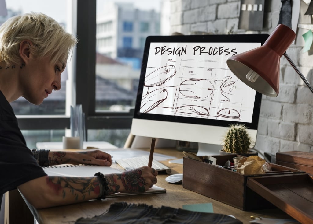 Künstlerin am Schreibtisch vor Mac, Design in Progress