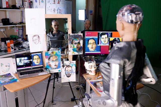 Roboter Sophia steht vor ihren selbst gemalten Porträts