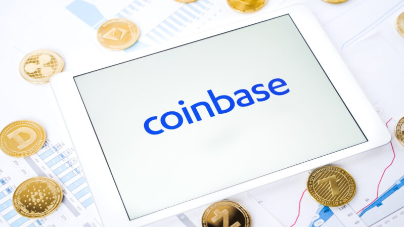 Coinbase Logo auf Tablet mit Krypto-Coins daneben