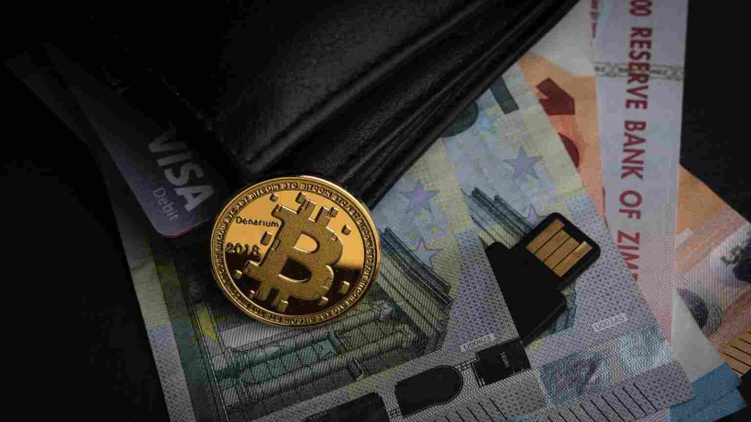 Bitcoin Münze und Euroscheine in einem Portemonnaie