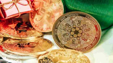 Cardano Münze und weitere physische Kryptos liegen auf weißem Untergrund