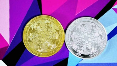 silberne und goldene Cardano Münzen auf buntem Hintergrund