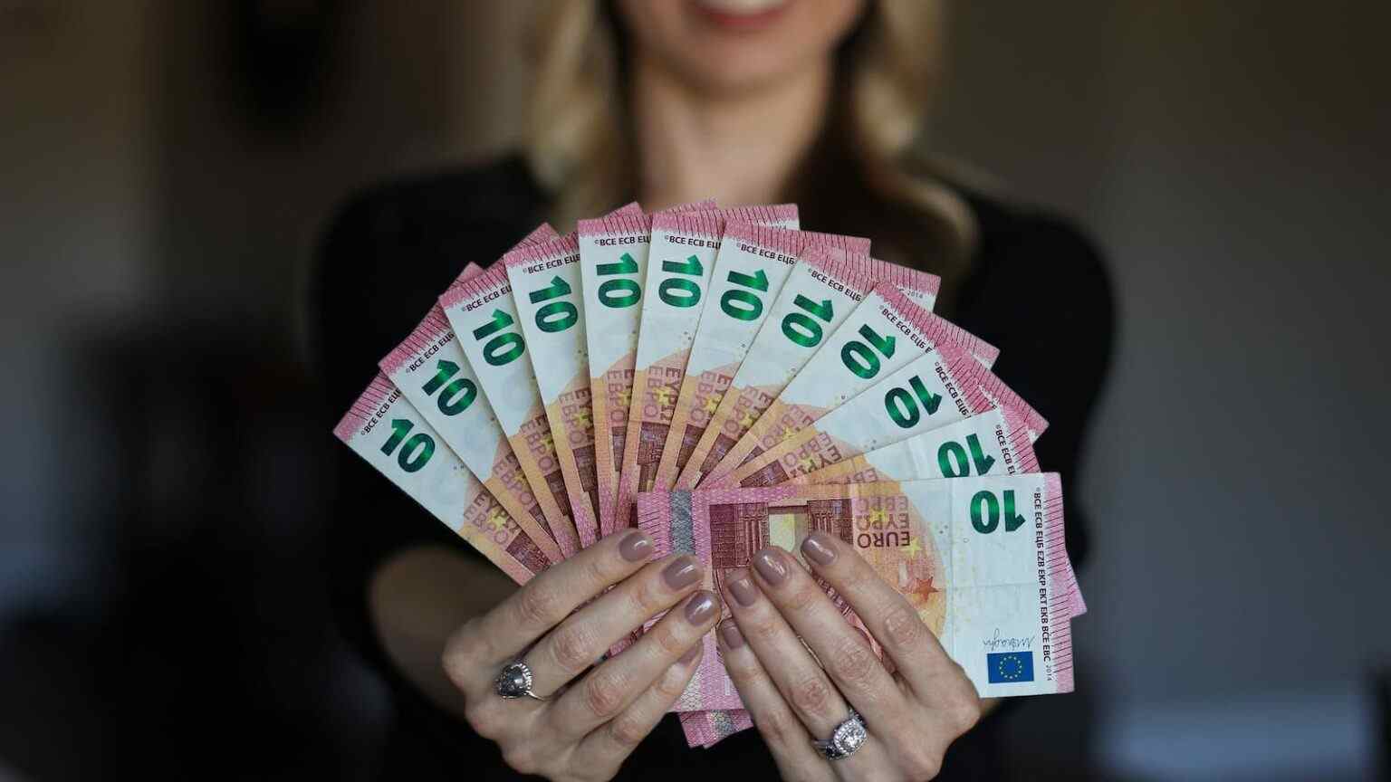 Eine Frau hält zahlreiche 10€ Scheine in den Händen