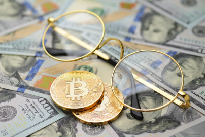 Bitcoin und Brille vor Dollarscheinen
