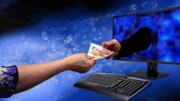 Hand reicht Geld durch einen Bildschirm