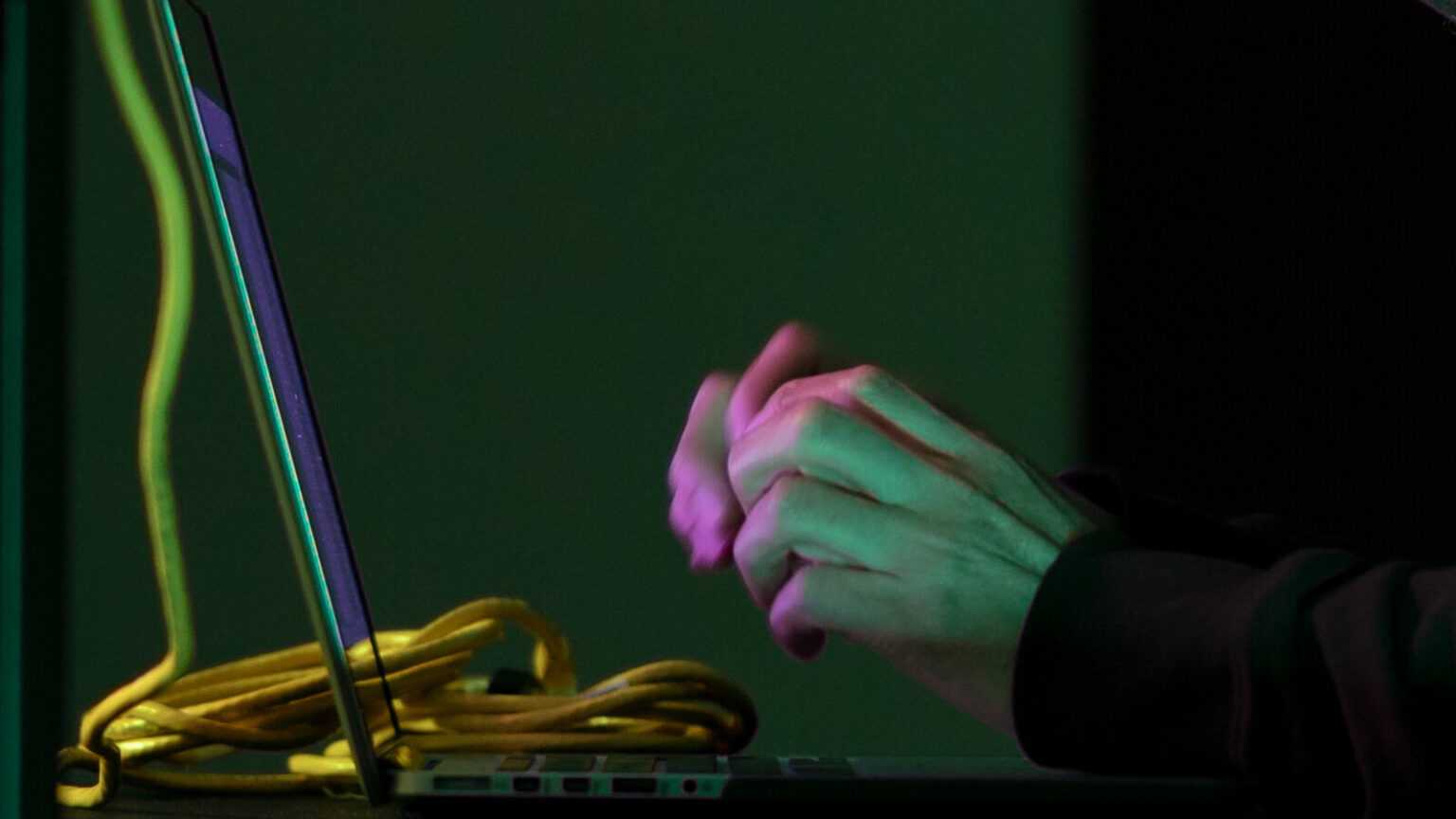 Hands in the dark in front of laptop keyboard Dark Mysterious Hacker