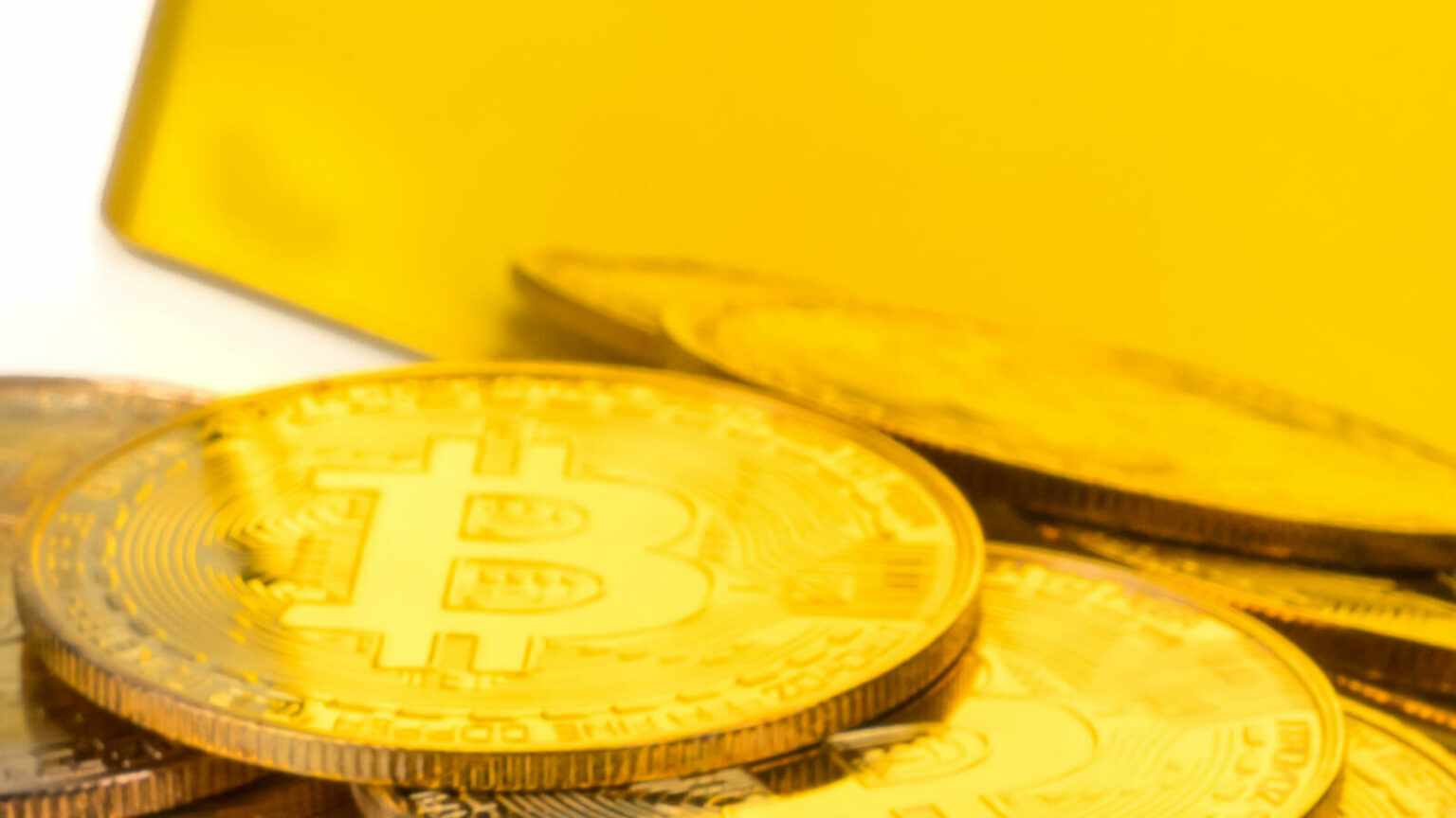 Goldbarren davor Bitcoinmünzen