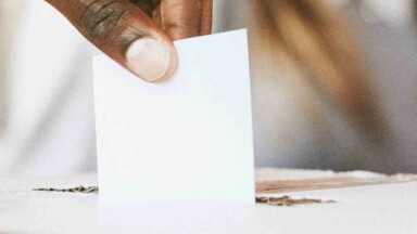 Stimmzettel in Box Wahlurne von Hand gehalten
