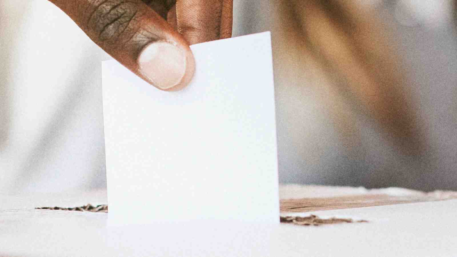 Stimmzettel in Box Wahlurne von Hand gehalten