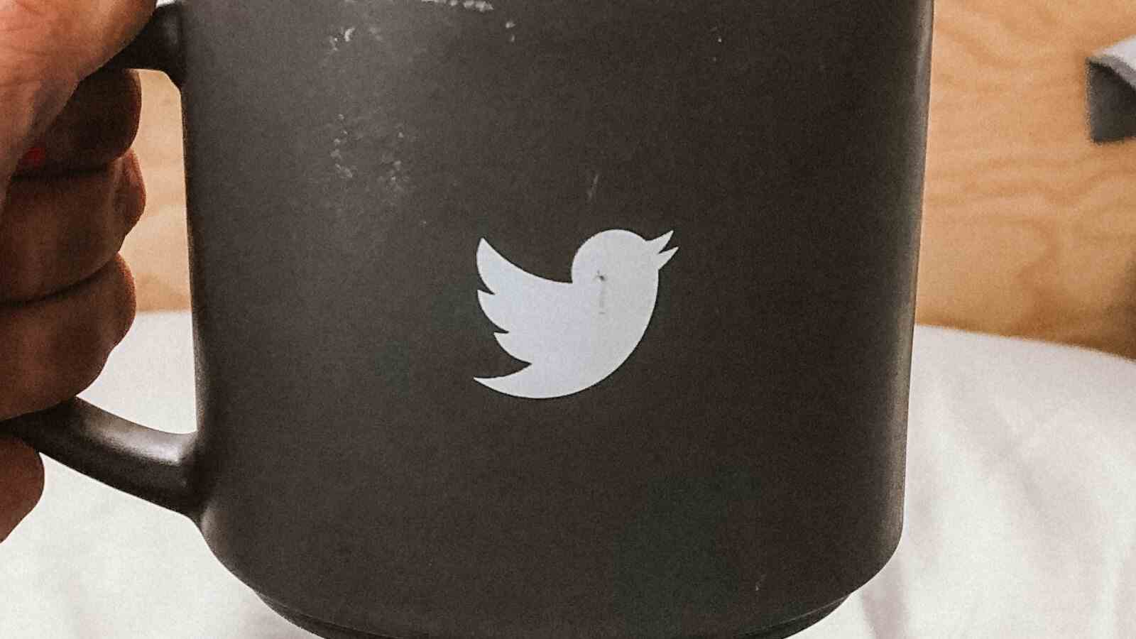 Mann hält schwarze Tasse mit Twitter Logo