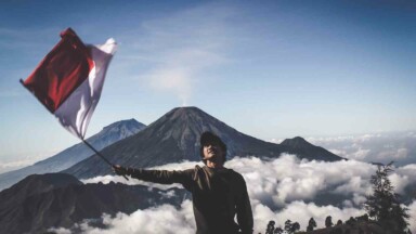 Mann schwenkt indonesische Flagge vor Vulkan