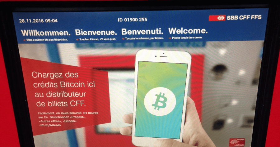Handy mit Bitcoin-Symbol vor einem SBB-Bitcoin-Automaten
