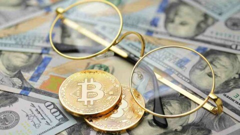 Bitcoin und Brille vor Dollarscheinen