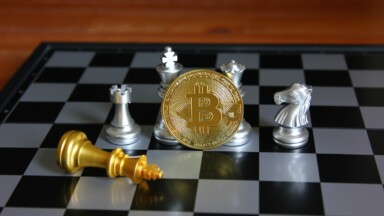 BTC Coin vor silbernen Schachfiguren auch Schachbrett