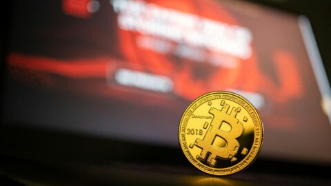 bitcoin münze stehend vor buntem hintergrund