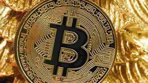Bitcoin Muenze vor Gold