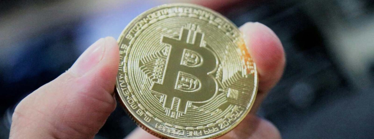 bitcoin m&uuml;nze wird zwischen fingern gehalten