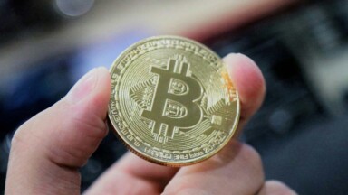 bitcoin münze wird zwischen fingern gehalten