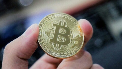 bitcoin münze wird zwischen fingern gehalten