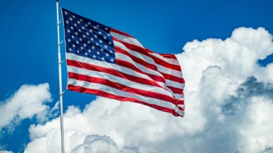 flagge der usa weht vor blauem himmel und weißen wolken