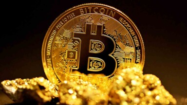 goldklumpen liegen vor einer stehenden bitcoin münze