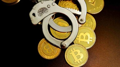 handschellen liegen auf krypto-muenzen