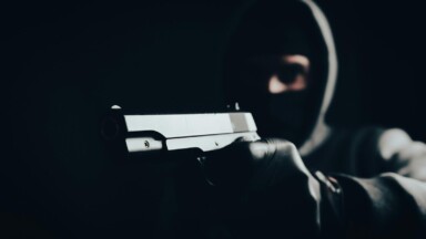 maskierter bankraeuber mit schusswaffe