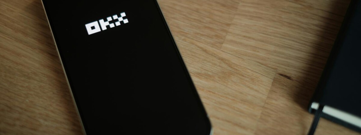 okx logo auf einem smartphone welches auf einem tisch liegt